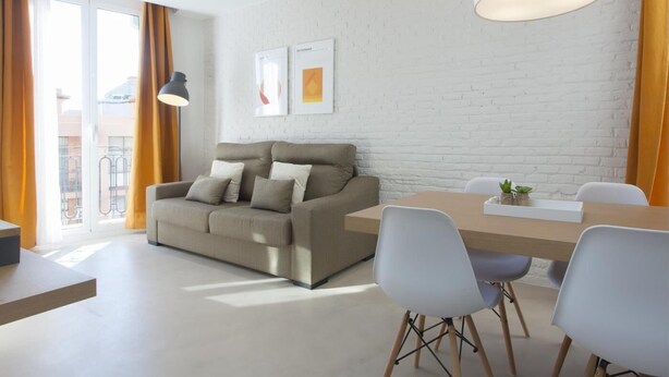 Ein modernes Wohnzimmer mit einer Couch, einem Esstisch, Stühlen und einer weißen Ziegelwand.