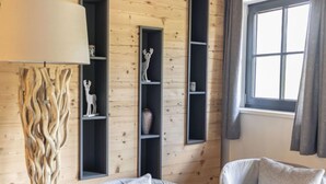 A cozy room with a wooden floor, a large lamp, two chairs, and built-in shelving with decorative items.