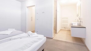 Camera d'albergo moderna con un letto, bagno con lavandino e specchio, e cabina armadio.