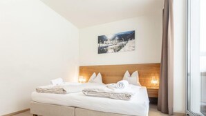 A double bed with a wooden headboard, a painting on the wall, and a window with curtains. - 1 Schlafzimmer & Pool by Interhome (Radstadt)