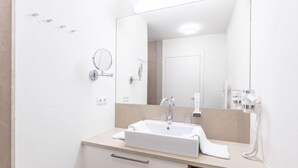 A modern bathroom with a large mirror, a sink, a towel, and a hairdryer. - 1 Schlafzimmer & Pool by Interhome (Radstadt)