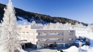 A modern multi-story building with a sign reading "Appartmenthotel" and "Tavern Restaurant." - 1 Schlafzimmer & Pool by Interhome (Radstadt)