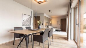 Un'area pranzo moderna con un tavolo e sedie in legno, una lampada a sospensione e un'ampia finestra con vista.