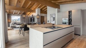 Una cucina moderna con isola centrale, travi in legno e zona pranzo con divano e tavolo.