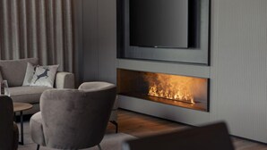Un soggiorno moderno con una televisione a schermo piatto montata a parete, un camino e confortevoli posti a sedere.