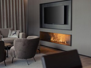Un salon moderne doté d’un téléviseur à écran plat fixé au mur, d’une cheminée et de sièges confortables.