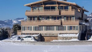 A multi-story building with balconies, a stone facade, and a view of snow-covered mountains. - mit 2 Schlafzimmern by Interhome (Westendorf)