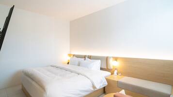 Hotellihuone, jossa on sänky, yöpöydät ja penkki.