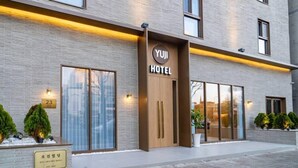 A modern hotel with a brick facade, large windows, and a sign indicating it is the Yuji Hotel. - Goyang Hotel Yuji (Goyang)