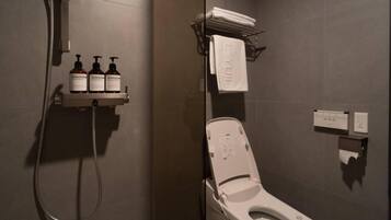 Un baño moderno con ducha, inodoro y un estante con artículos de aseo.