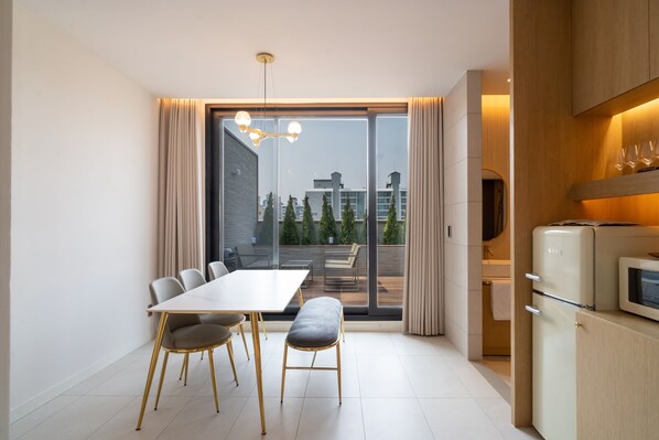 A modern kitchen with a dining area, a sliding glass door to a balcony, and a built-in microwave. - Goyang Hotel Yuji (Goyang)