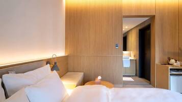 Une chambre d’hôtel moderne équipée d’un lit, d’une table de chevet, d’une lampe et offrant une vue sur la salle de bain.