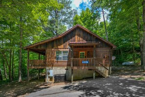 A wooden cabin with a porch, a small deck, and a sign indicating it is 130 miles from the nearest town.