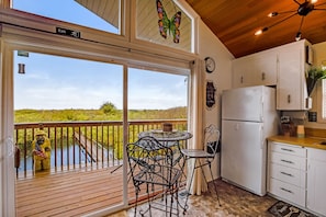 A kitchen with a view of a green landscape, a table with chairs, and a decorative butterfly.