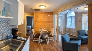 A modern living room with a wooden dining table, two chairs, a sofa, and a coffee table. - Free Breakfast_In Downtown_Main Street Apt A (Bar Harbor)