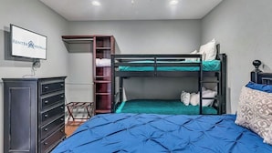 A bedroom with bunk beds, a dresser, a ceiling fan, and a television on the wall. - Treehouse 1414: Stunning Lake Views, Boat Slip Included, Free Tickets & Prime Location (Branson)