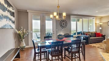 A dining area with a wooden table and chairs, a chandelier, and a clock on the wall.