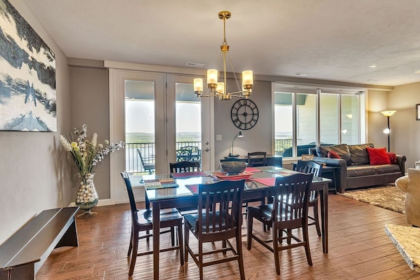 A dining area with a wooden table and chairs, a chandelier, and a clock on the wall.