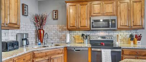 A kitchen with wooden cabinets, a microwave, a dishwasher, a stove, and a sink.