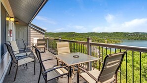 A balcony with a table and chairs, overlooking a lake and greenery. - Incredible Lake Views, Boat Slip Included, 3 Bedrooms & Free Tickets Near Silver Dollar City (Branson)