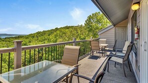 A balcony with a glass table and chairs, overlooking a forested area. - Incredible Lake Views, Boat Slip Included, 3 Bedrooms & Free Tickets Near Silver Dollar City (Branson)