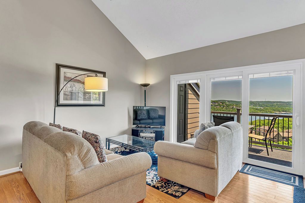 A living room with two sofas, a TV, and a balcony with a view.
