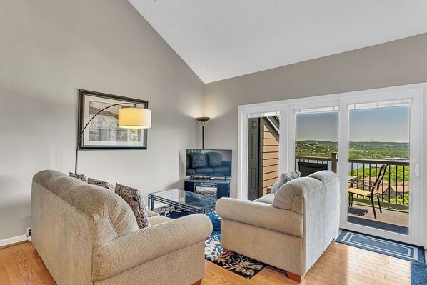 A living room with two sofas, a TV, and a balcony with a view.