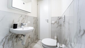 Une salle de bain avec un lavabo blanc, un miroir et des toilettes.