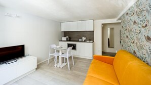 Un espace de vie compact comprenant un coin cuisine, un coin repas, un téléviseur et un canapé.