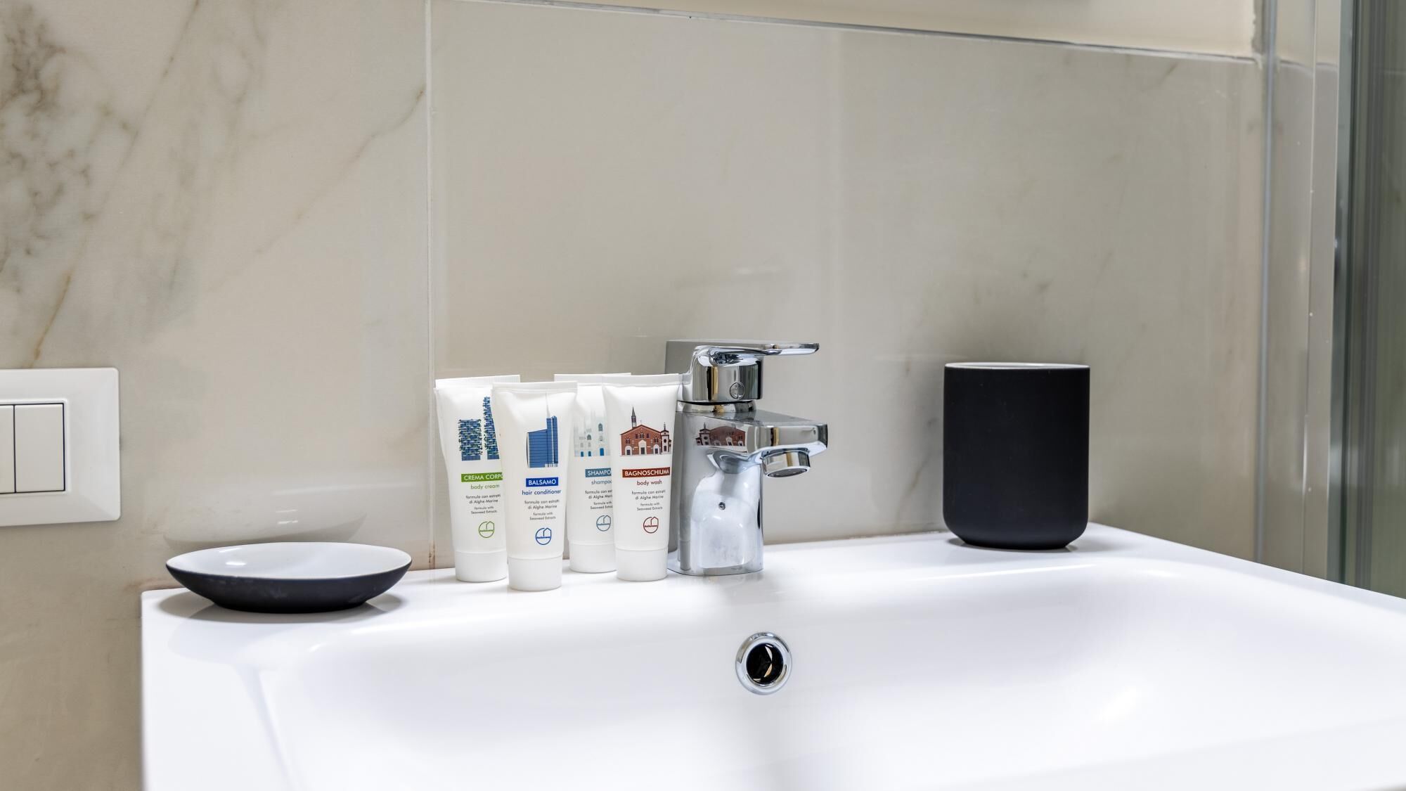 Un lavandino da bagno con articoli da toilette, un rubinetto e una tazza.