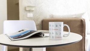 A white mug with Italian symbols and the text "italianway" on a small round table. - Italianway - The B Village Standard - 02 (Milan)