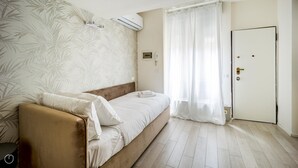 A bedroom with a bed, a bedside table, a wall-mounted air conditioner, and a door. - Italianway - The B Village Standard - 02 (Milan)