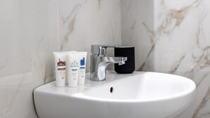 A bathroom sink with a chrome faucet and three toiletry bottles. - Italianway - The B Village Standard - 02 (Milan)