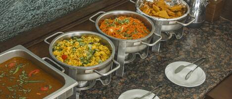 Una mesa de buffet con varios platos servidos en recipientes metálicos.