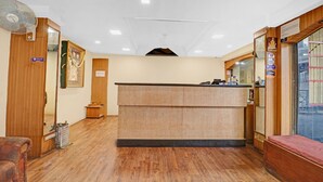 Una zona de recepción con un mostrador de madera, un ventilador de pie y un mueble de madera pequeño.