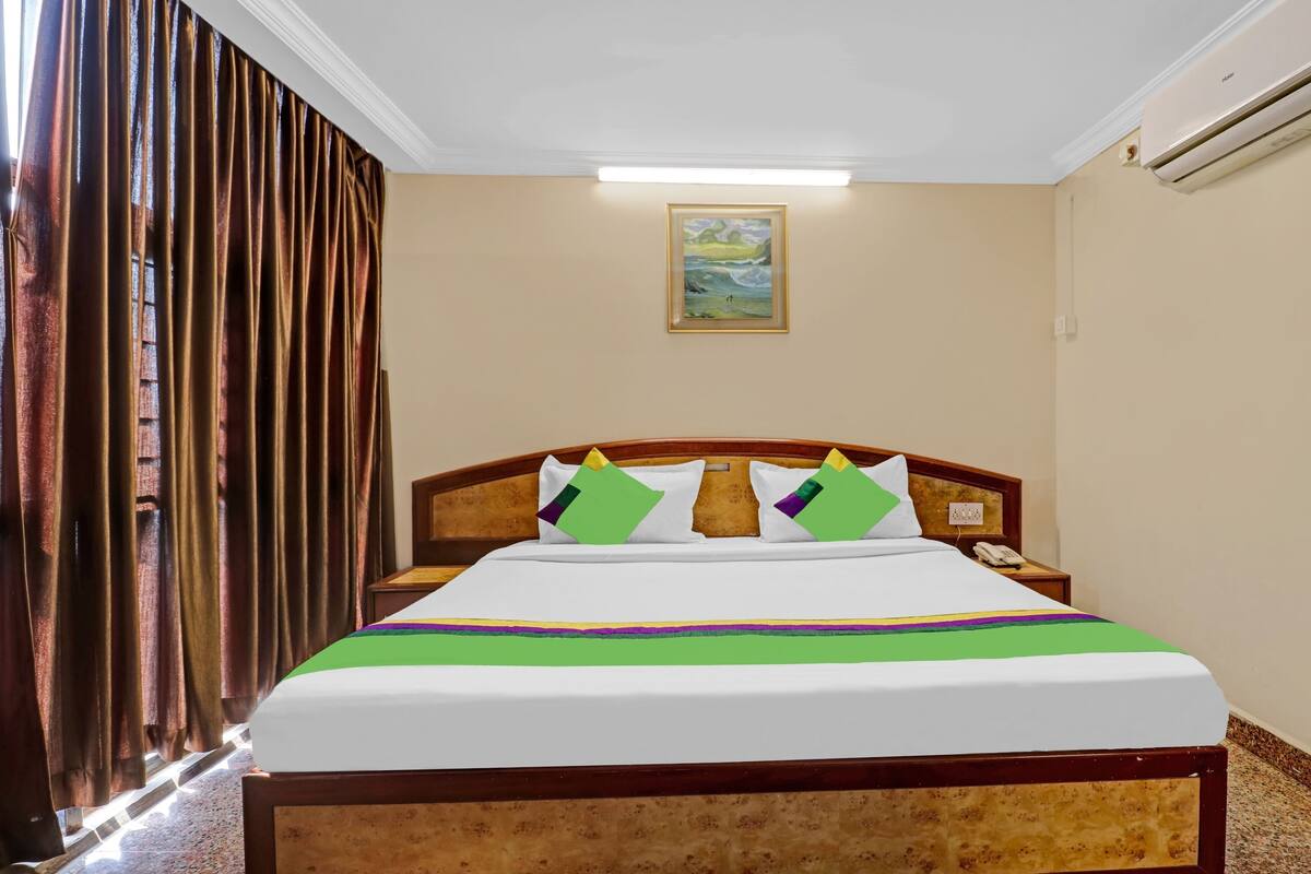 Een hotelkamer met een bed, een schilderij aan de muur en een airconditioning.