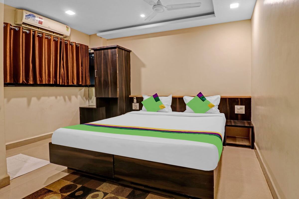 Een hotelkamer met een bed, een kledingkast, een plafondventilator en een raam met gordijnen.