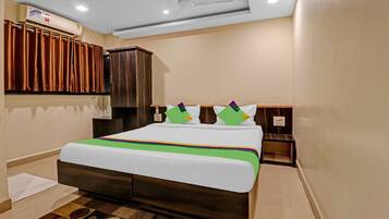 Una habitación de hotel con una cama, un armario, un ventilador de techo y una ventana con cortinas.