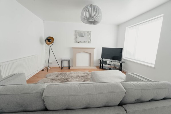 Una sala de estar moderna con un sofá gris, una chimenea, un televisor y una lámpara de pie.