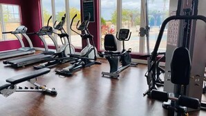 Un gimnasio con cintas de correr, elípticas y equipo de levantamiento de pesas.