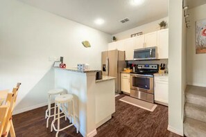 Enjoy cooking in this well-equipped kitchen with a central island, microwave, stove, and refrigerator.