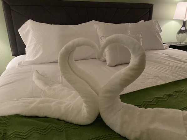 A bed with white linens and a green bedspread.
