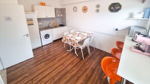 Una cocina compacta con lavadora, una mesa de comedor con sillas y un tostador.