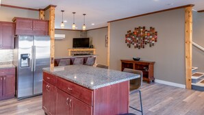 Una cocina moderna con encimeras de granito, refrigerador de acero inoxidable, armarios de madera y una isla integrada.