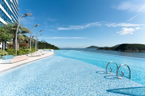 A swimming pool with clear blue water, surrounded by lounge chairs and a modern building. - The Fullerton Ocean Park Hotel Hong Kong (Hong Kong)
