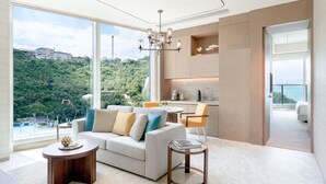 A modern living room with a large window, a sofa, a coffee table, and a dining area.