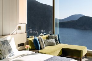 A modern hotel room with a large window offering a view of a lake and mountains. - The Fullerton Ocean Park Hotel Hong Kong (Hong Kong)