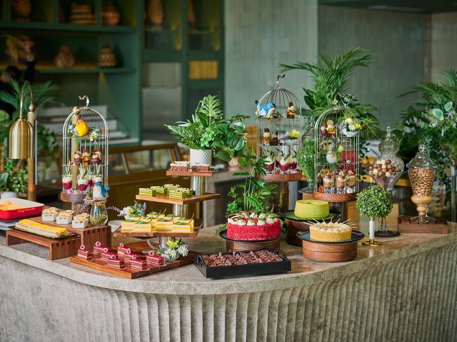 A buffet with various food items and decorative birdcages.