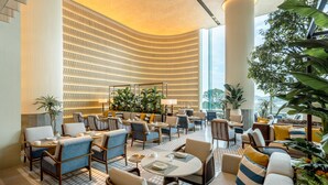 A spacious lobby with seating areas, a patterned wall, and large windows.