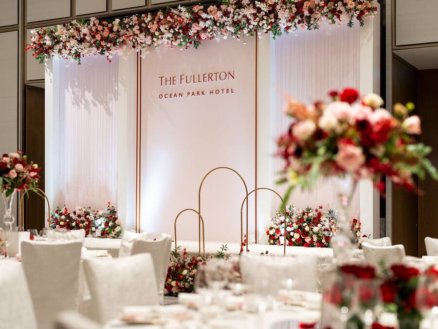 A wedding reception setup at The Fullerton Ocean Park Hotel with tables set for guests, floral centerpieces, and a backdrop with the hotel's name.